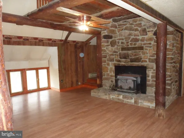 a view of an empty room with wooden floor fireplace and a window