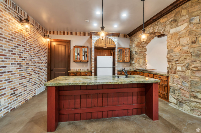 811 South High Ridge Drive Alpine, UT 84004 - Photo 43 of 98 Kitchen featuring glass insert cabinets, freestanding refrigerator, dark stone countertops, pendant lighting, and a kitchen island with sink