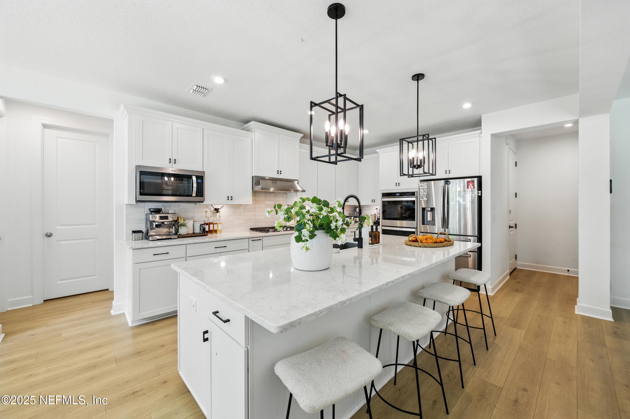 177 Windwalker Drive St. Augustine, FL 32092 - Photo 10 of 30 a kitchen with stainless steel appliances kitchen island granite countertop a stove a sink a microwave a refrigerator and white cabinets with wooden floor
