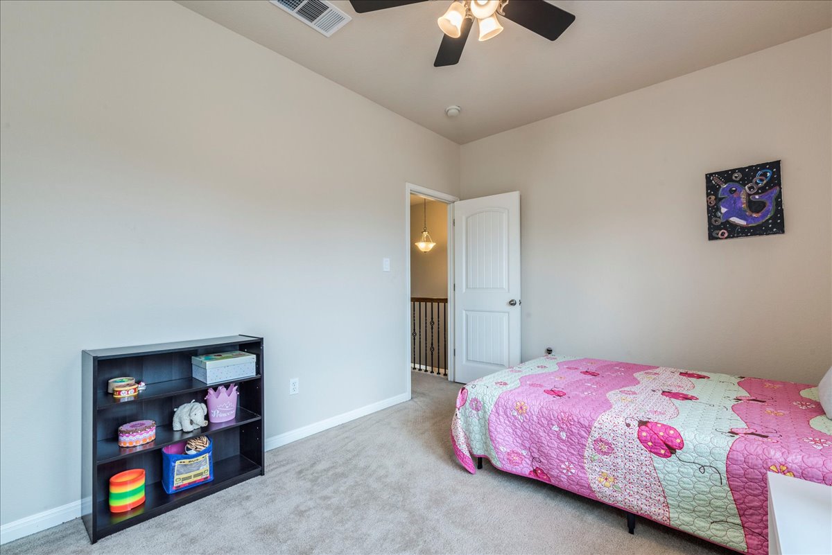 18628 Wind Valley Way Pflugerville, TX 78660 - Photo 17 of 33 a bedroom with a bed and a book shelf