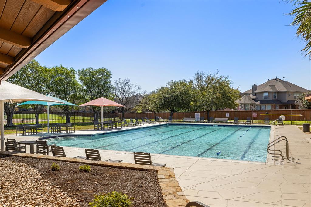 18628 Wind Valley Way Pflugerville, TX 78660 - Photo 29 of 33 a view of a swimming pool with lawn chairs under an umbrella
