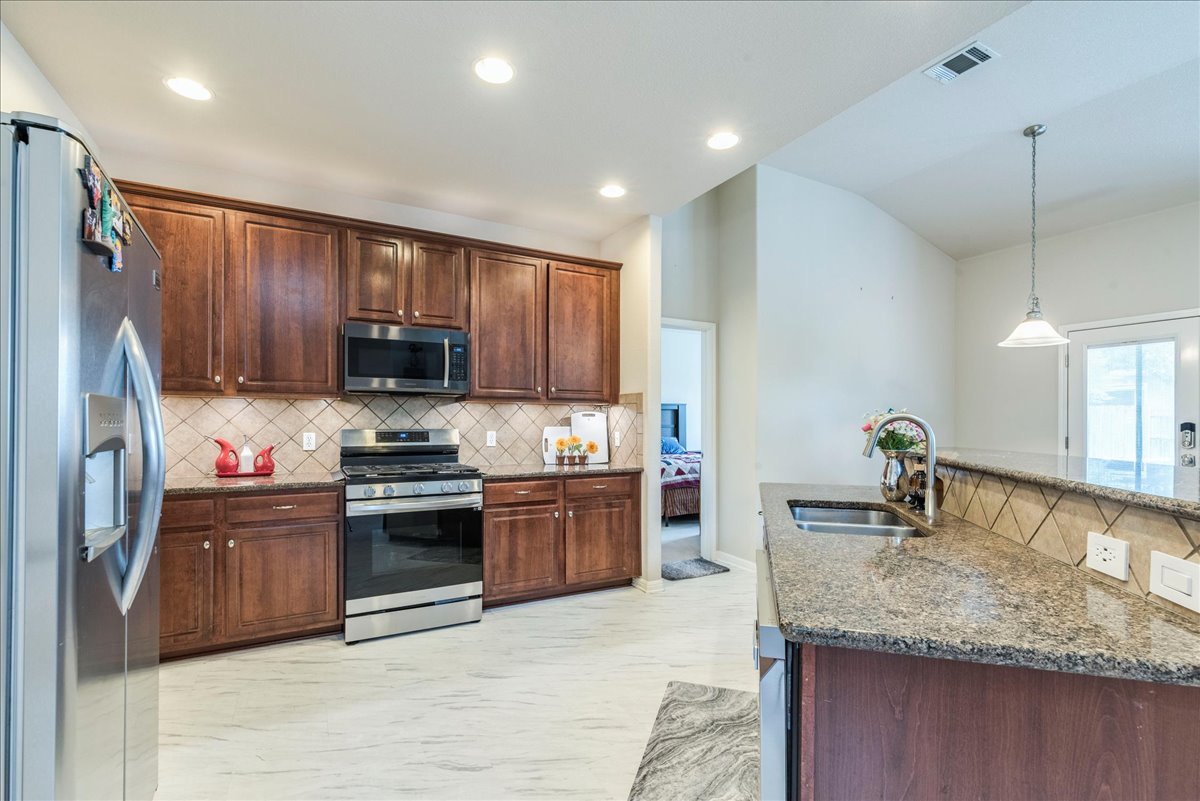 18628 Wind Valley Way Pflugerville, TX 78660 - Photo 8 of 33 a kitchen with stainless steel appliances granite countertop a sink stove and refrigerator