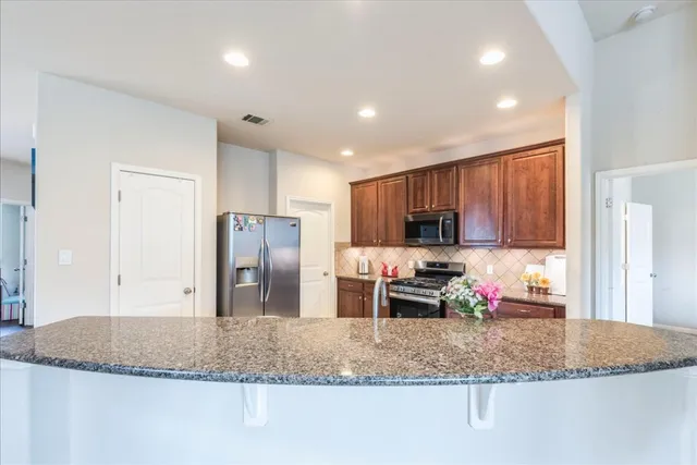 a kitchen with stainless steel appliances granite countertop a sink refrigerator and cabinets