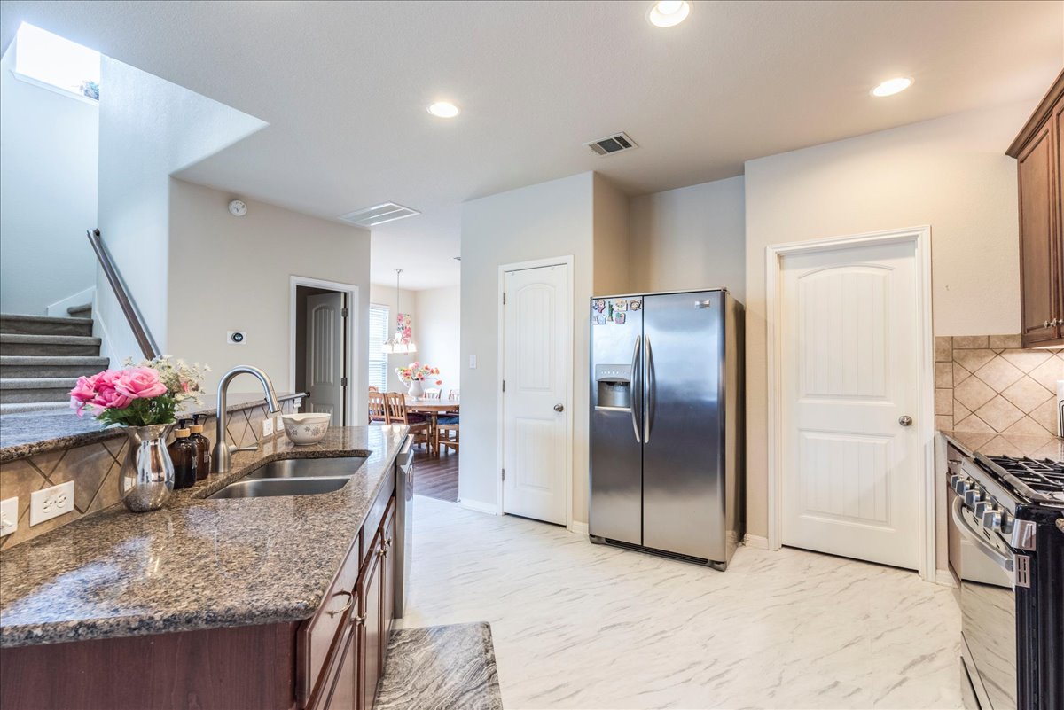18628 Wind Valley Way Pflugerville, TX 78660 - Photo 9 of 33 a kitchen with stainless steel appliances granite countertop a refrigerator and a sink