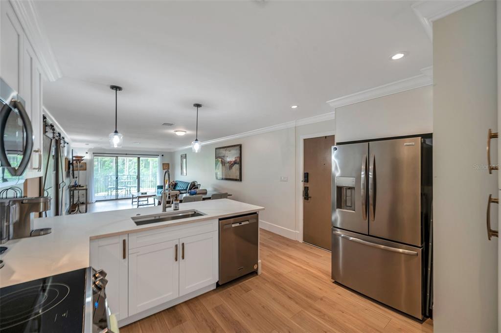 29147 Bay Hollow Drive, Unit 3224 Wesley Chapel, FL 33543 - Photo 9 of 89 a kitchen with a refrigerator a sink dishwasher a stove and a dining table with wooden floor