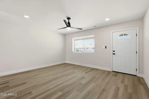 a view of an empty room with wooden floor and a window