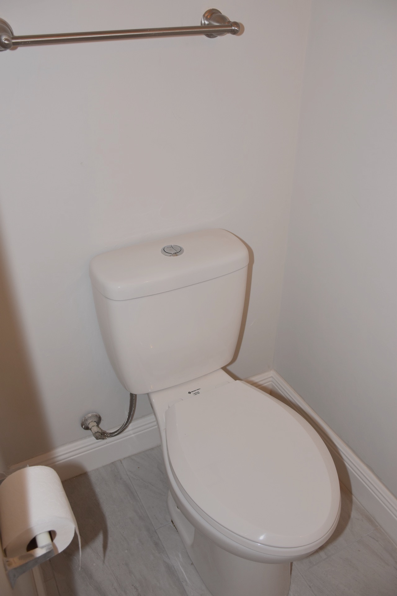 1810 Rawhide Loop Round Rock, TX 78681 - Photo 10 of 29 White toilet with top-mounted flush button, accompanied by a brushed nickel towel bar and white baseboards on wood-finish flooring