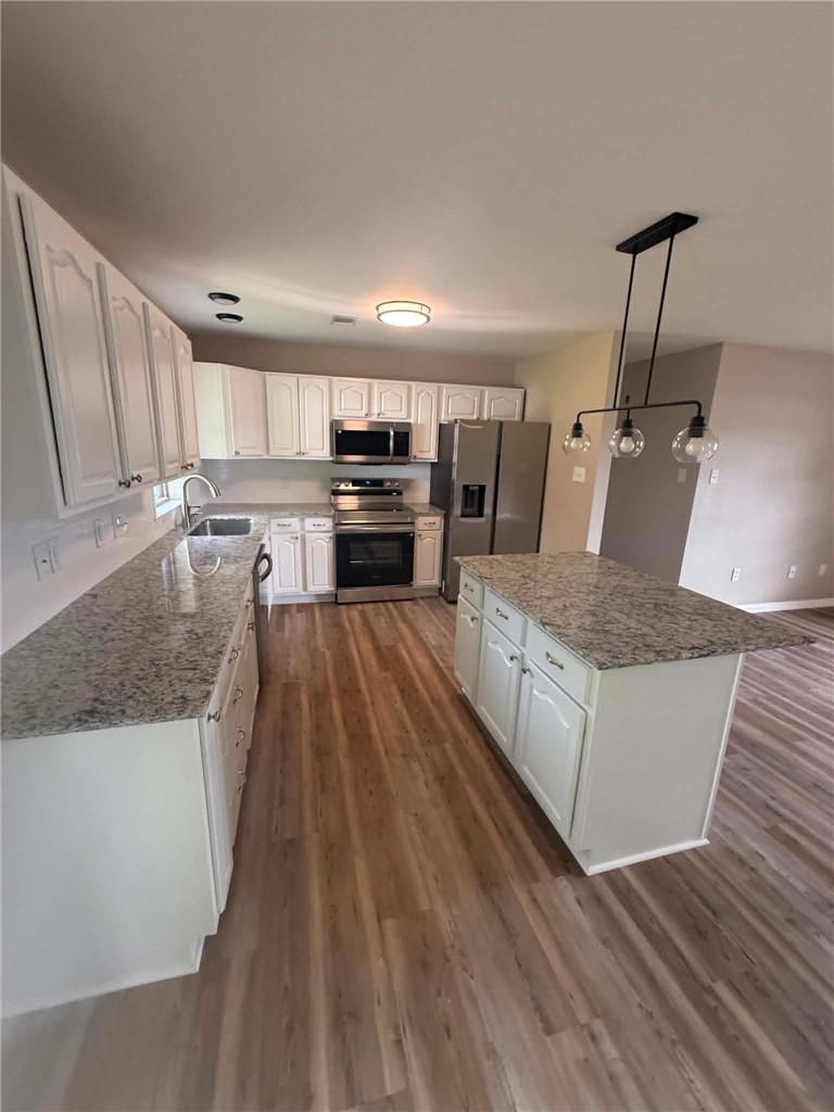 2106 Military Road Dardanelle, AR 72834 - Photo 3 of 16 Kitchen featuring white cabinetry, granite countertops, stainless steel appliances, a center island, and wood-finish flooring