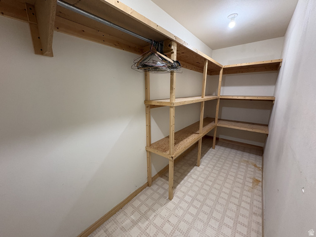 486 West 120 North Orem, UT 84057 - Photo 23 of 30 Storage room with patterned flooring, built-in wooden shelving, and a hanging rod