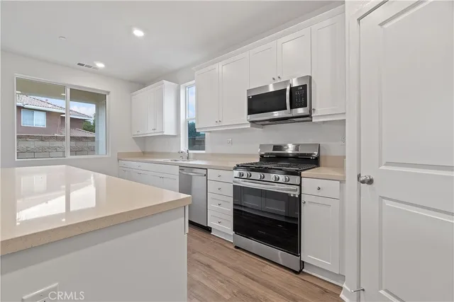 a kitchen with stainless steel appliances white cabinets and a stove top oven