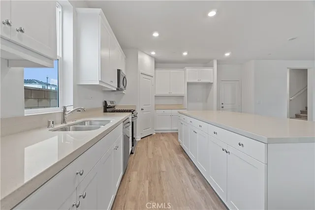 a large white kitchen with a large window and stainless steel appliances