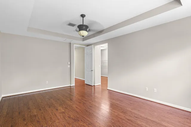 a view of an empty room with wooden floor and a ceiling fan