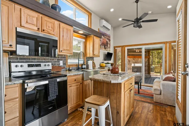 a open kitchen with stainless steel appliances granite countertop a stove top oven a refrigerator a stove and a dining table with wooden floor