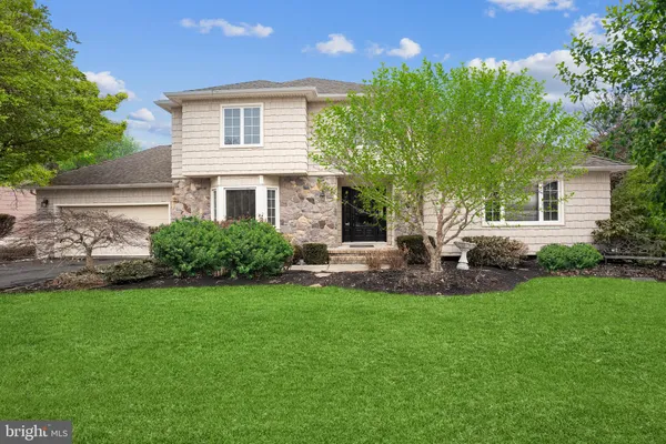 a front view of a house with a yard and a tree