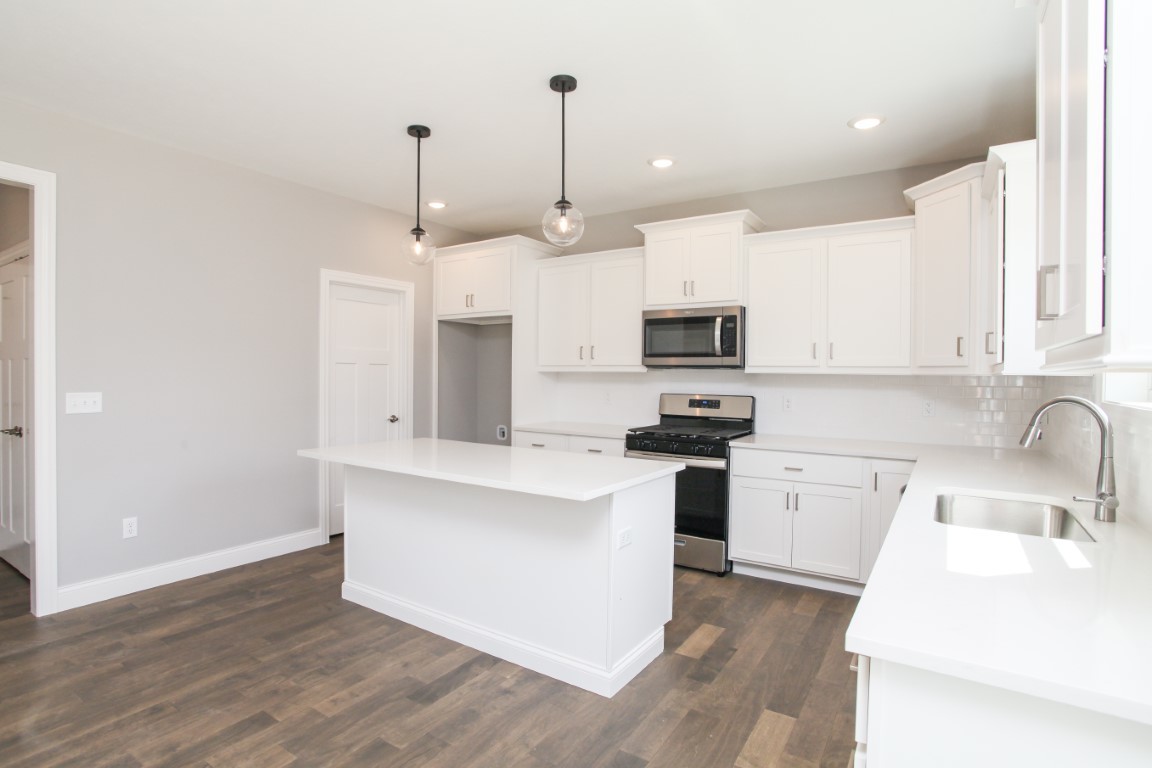 9 Brookstone Circle Bloomington, IL 61704 - Photo 10 of 40 a kitchen with stainless steel appliances granite countertop a sink a stove a refrigerator and white cabinets with wooden floor