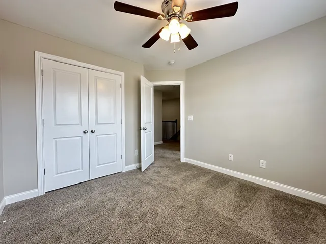 an empty room with closet and a ceiling fan