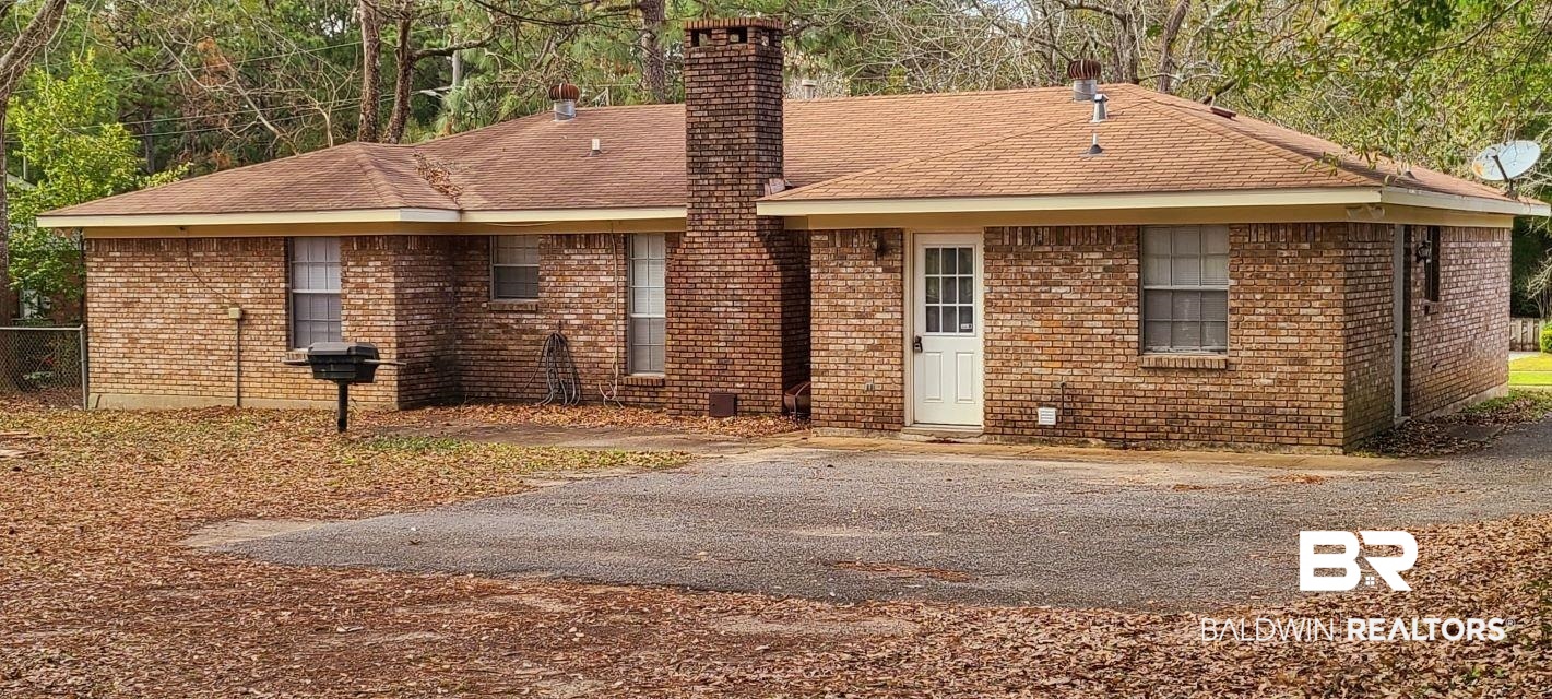 5305 Wilhelm Drive Mobile, AL 36618 - Photo 16 of 16 Rear view of property featuring aphalt driveway, brick siding, and a chimney