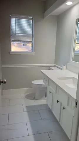 a bathroom with a granite countertop sink a toilet and mirror