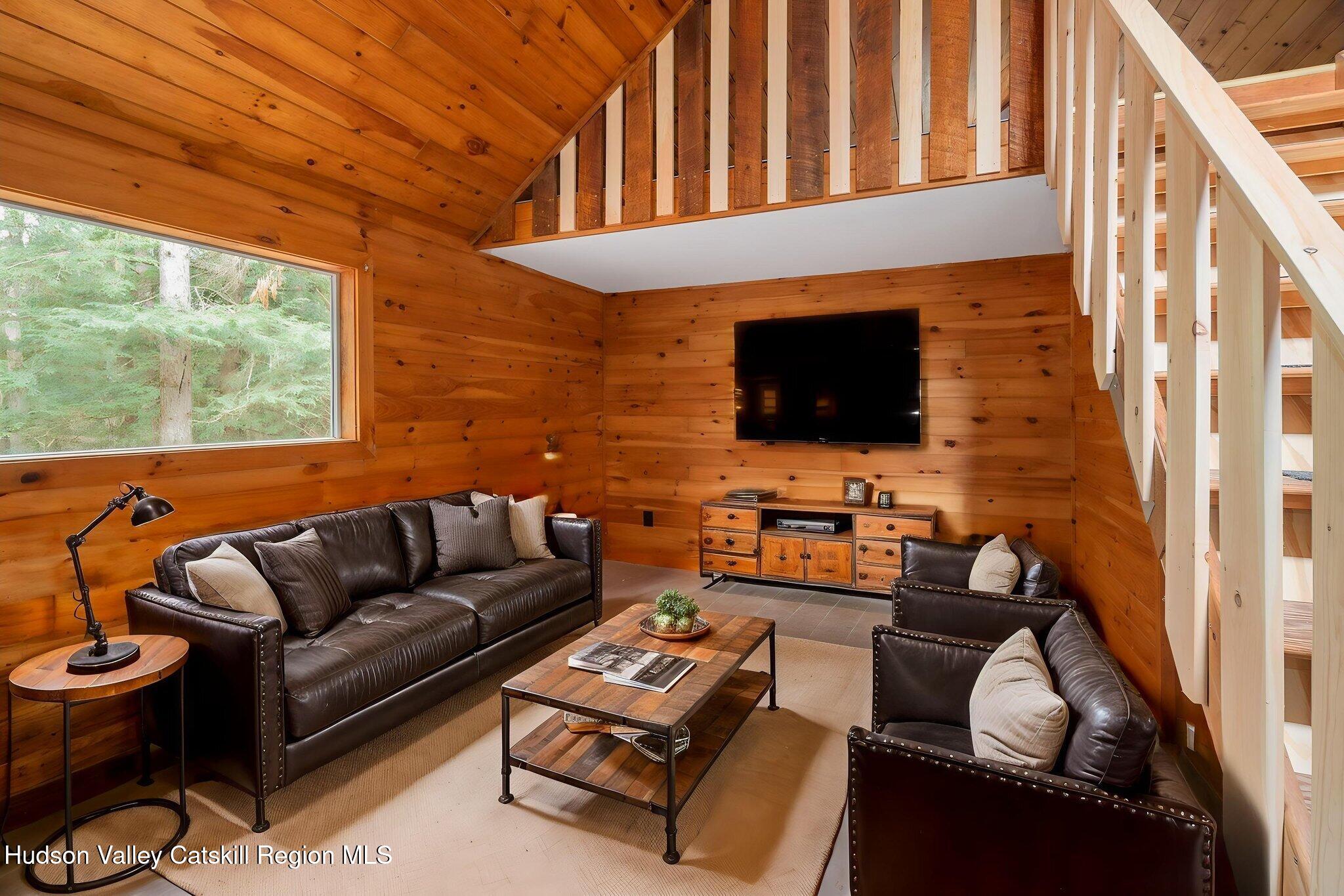 202 Blakesley Road, Unit PRIVATE Gilboa, NY 12076 - Photo 13 of 39 a living room with furniture a flat screen tv and a floor to ceiling window