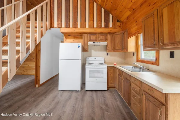 a kitchen with a refrigerator a sink and dishwasher with wooden floor