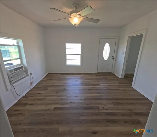 a view of an empty room with wooden floor and a window