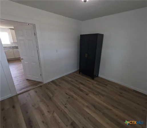 an empty room with wooden floor and entrance