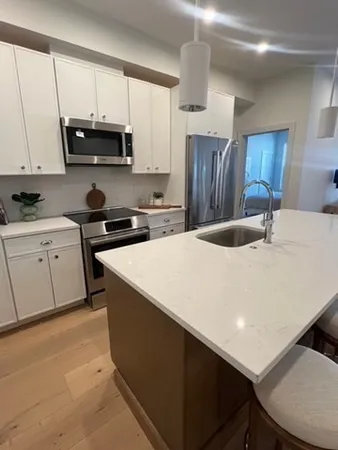 a kitchen with stainless steel appliances a sink a stove a microwave a refrigerator a counter space and cabinets