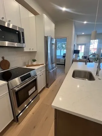 a kitchen with stainless steel appliances a stove a microwave a sink a refrigerator and white cabinets