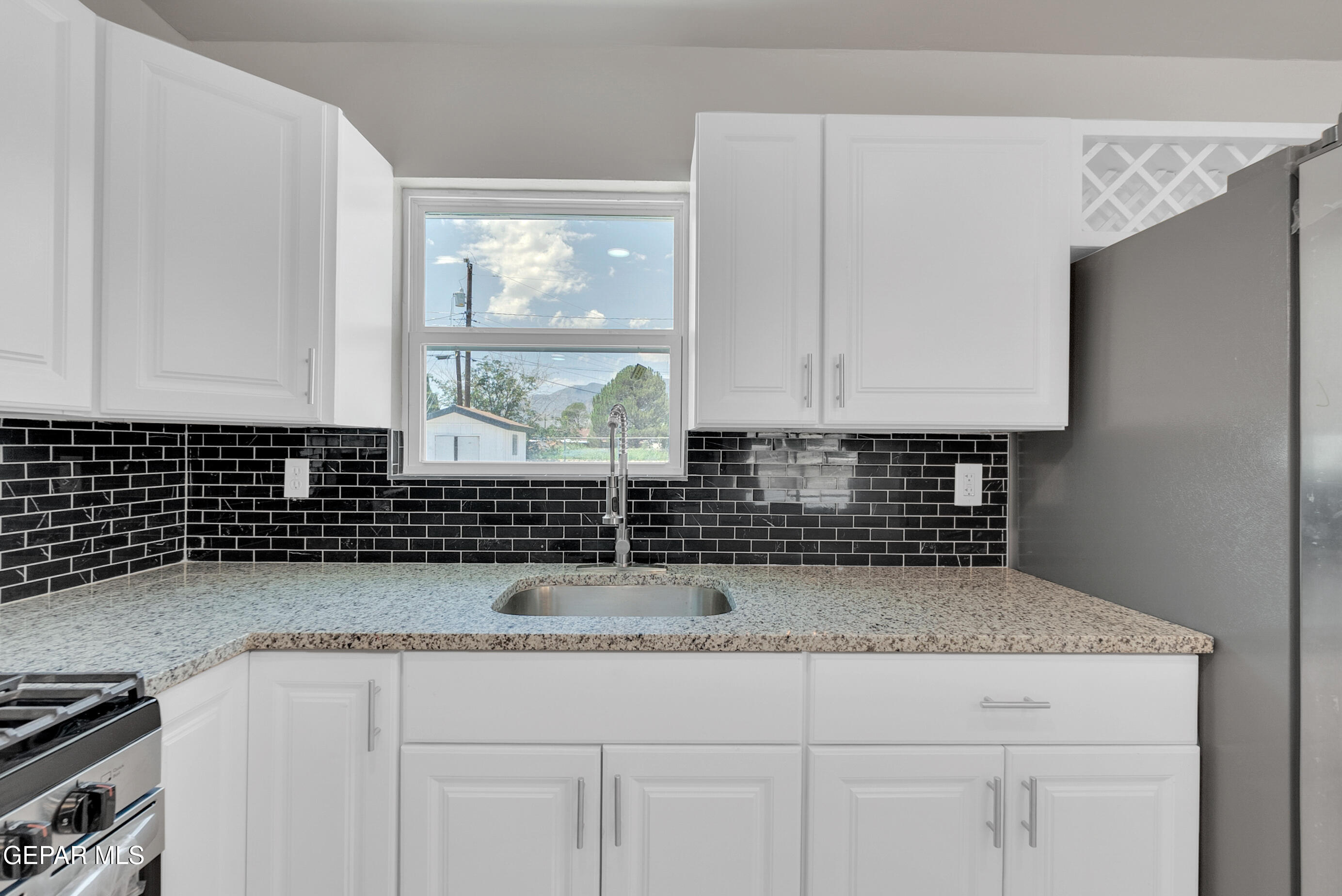 10141 Alcan Street El Paso, TX 79924 - Photo 11 of 49 a kitchen with granite countertop a sink a stove and cabinets