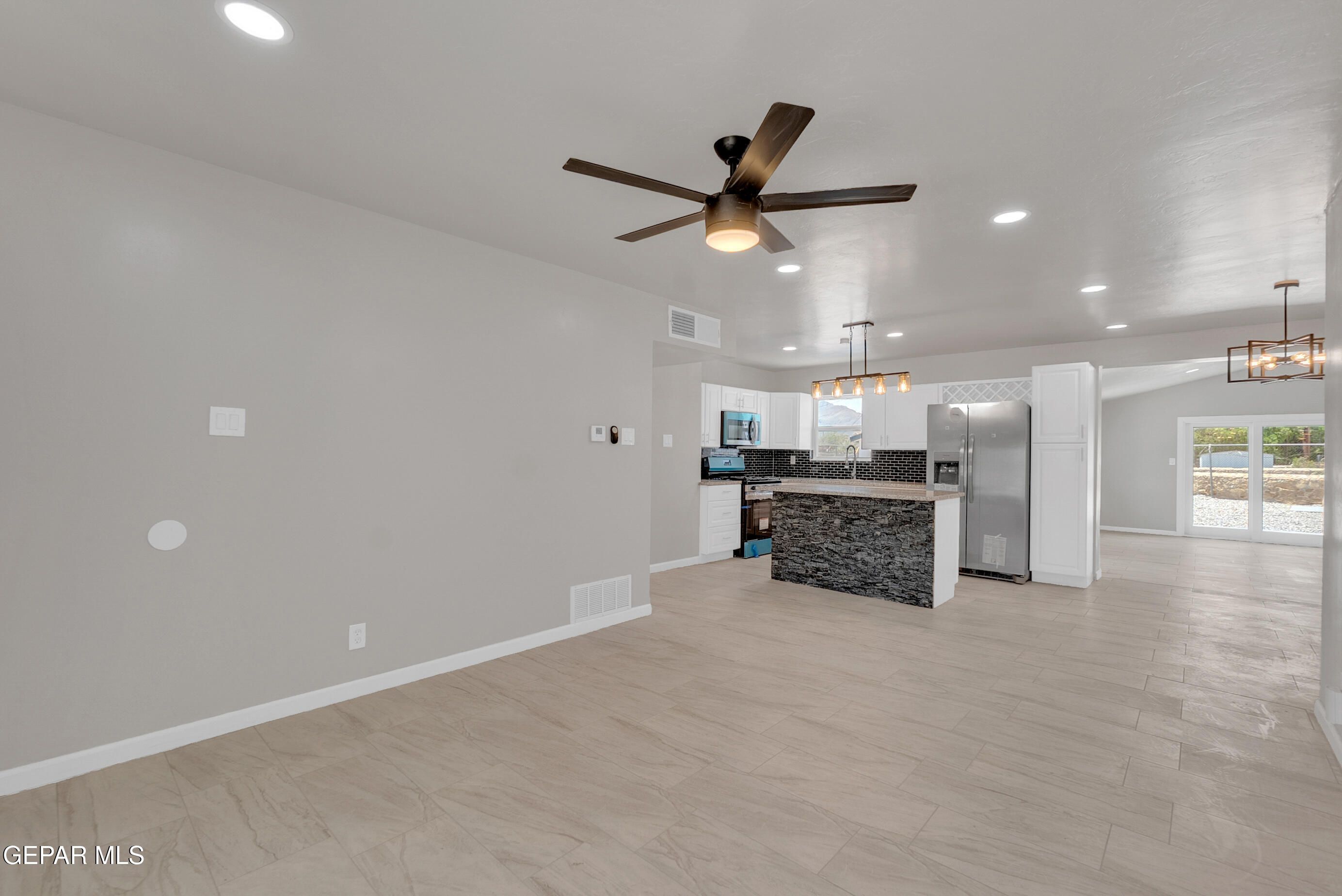 10141 Alcan Street El Paso, TX 79924 - Photo 7 of 49 an empty room with kitchen and ceiling fan