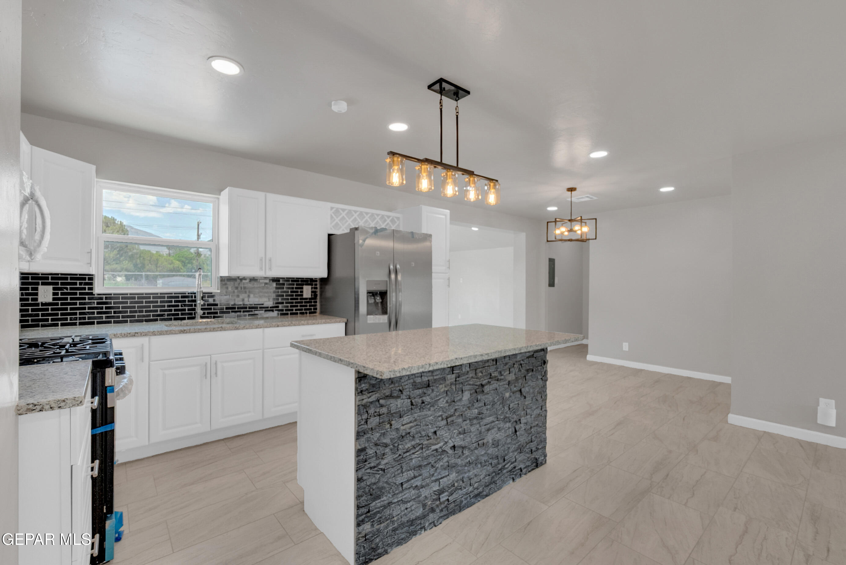 10141 Alcan Street El Paso, TX 79924 - Photo 8 of 49 a kitchen with kitchen island granite countertop a stove a sink a center island and cabinets