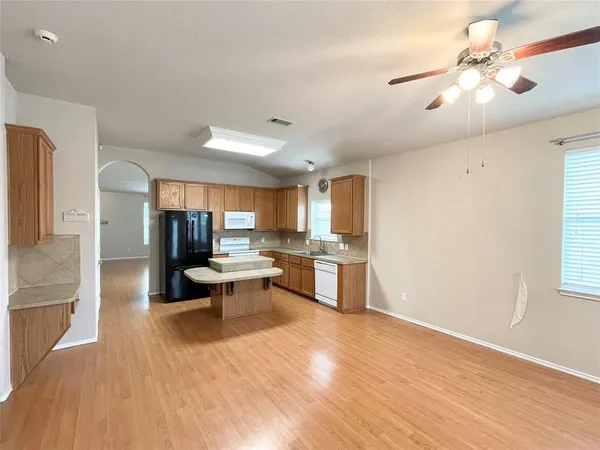 a living room with couches and kitchen view with wooden floor