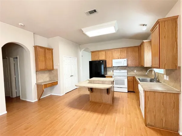 a living room with a sink and a wooden floor