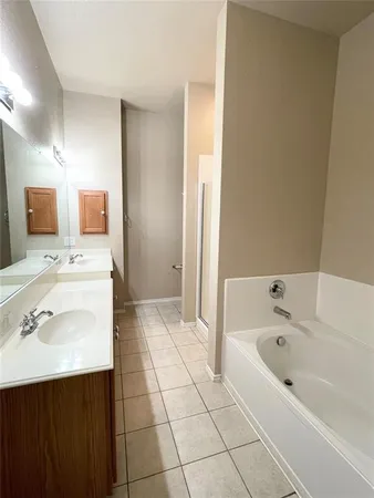 a bathroom with a tub sink double vanity and mirror