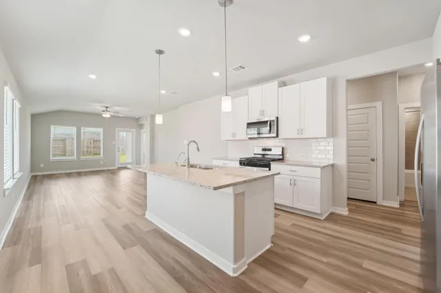 a kitchen with stainless steel appliances kitchen island hardwood floor sink and stove