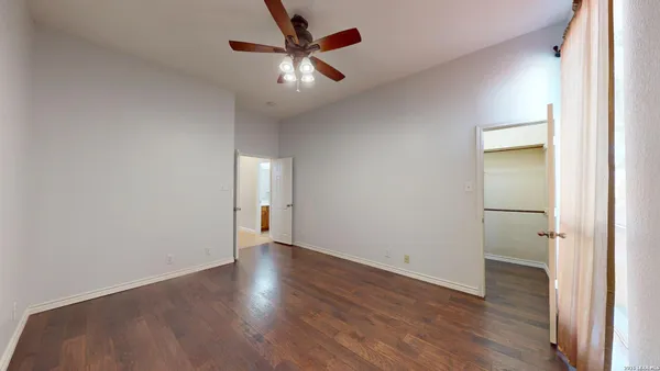 a view of an empty room with window and wooden floor