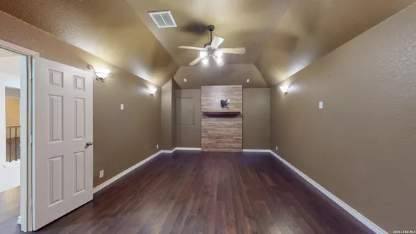 an empty room with wooden floor and a ceiling fan