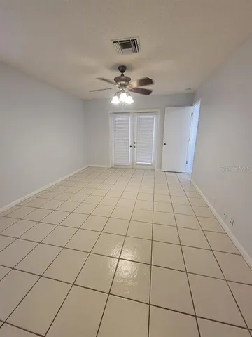 a view of an empty room and chandelier fan