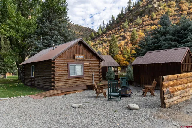 a view of backyard with a table and chairs and a large tree