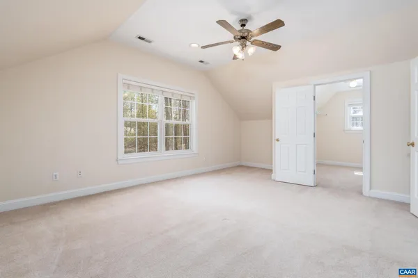 an empty room with chandelier fan and windows
