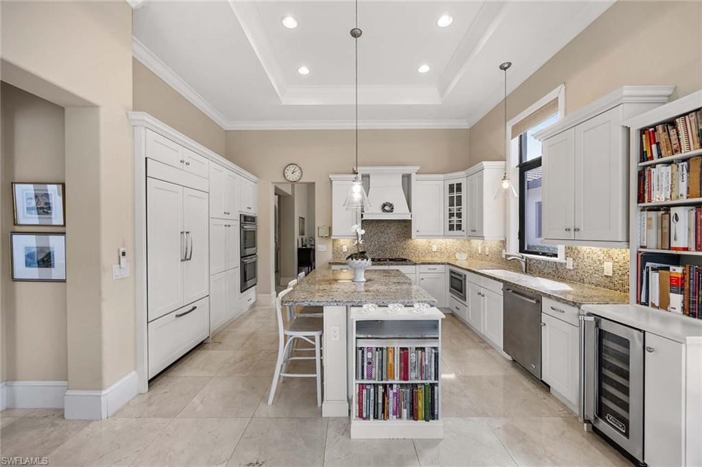 2277 Residence Circle Naples, FL 34105 - Photo 24 of 41 a large kitchen with stainless steel appliances kitchen island granite countertop a refrigerator a stove a sink dishwasher and white cabinets with wooden floor
