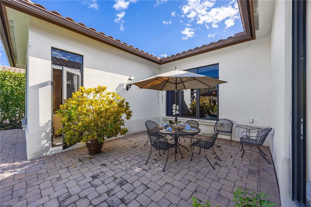 2277 Residence Circle Naples, FL 34105 - Photo 30 of 50 a view of a patio with a table and chairs under an umbrella