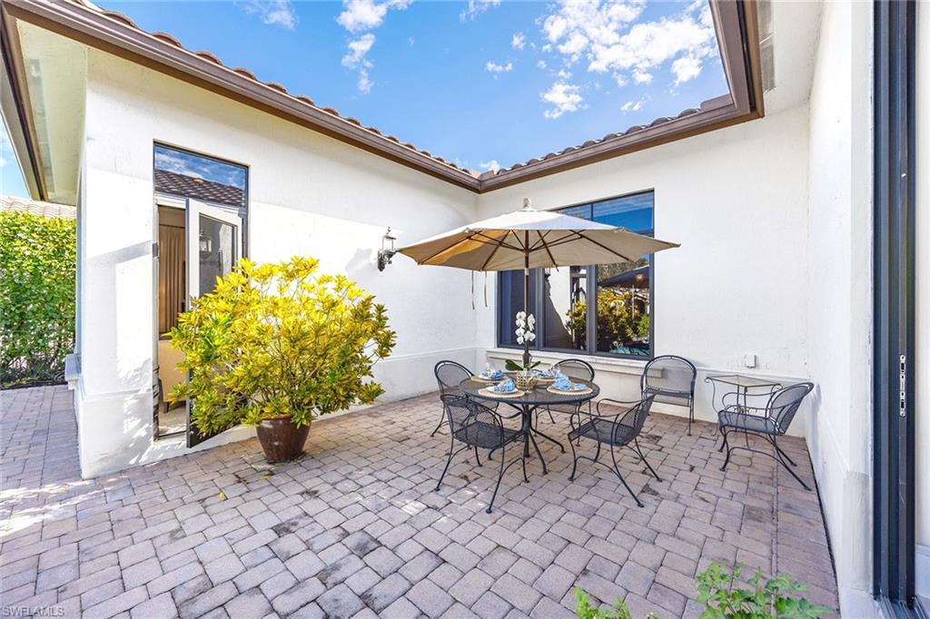 2277 Residence Circle Naples, FL 34105 - Photo 6 of 41 a view of a patio with a table and chairs under an umbrella