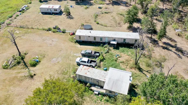 an aerial view of residential house with pool and trees all around