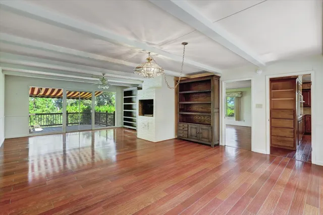 an empty room with wooden floor closet and windows
