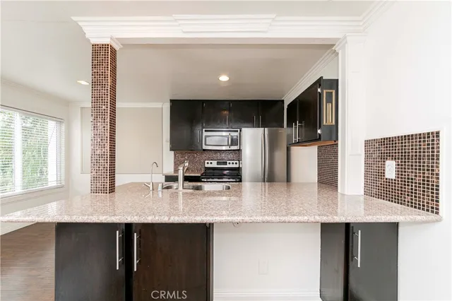 a kitchen with stainless steel appliances granite countertop a sink refrigerator and cabinets