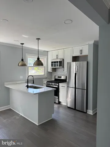 a kitchen with stainless steel appliances a refrigerator a stove a sink and white cabinets