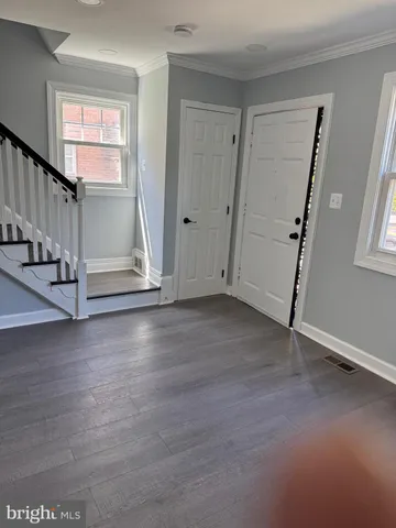 a view of an empty room with wooden floor and stairs