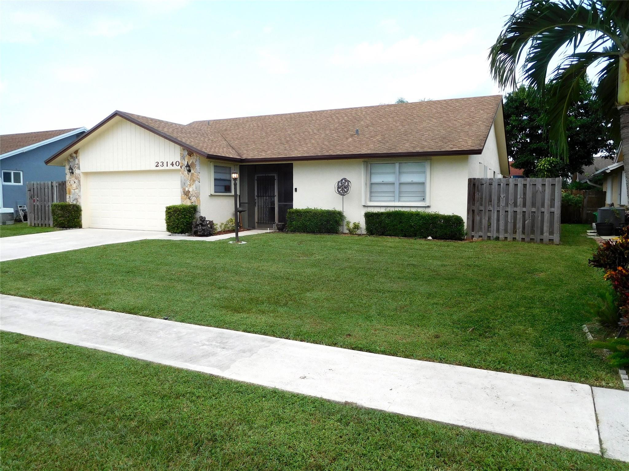 23140 Southwest 55th Avenue Boca Raton, FL 33433 - Photo 5 of 39 a front view of a house with a yard and garage