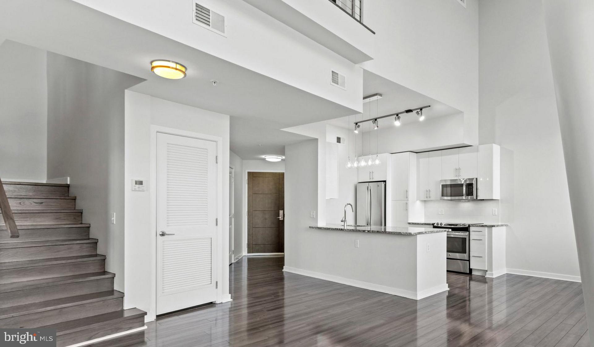 8300 Wisconsin Avenue, Unit 1B1447 Bethesda, MD 20814 - Photo 15 of 25 an empty room with wooden floor and a kitchen